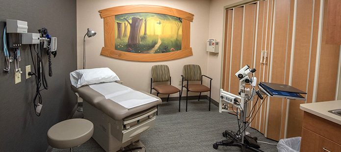 Medical exam room with an exam table, two chairs, and some equipment