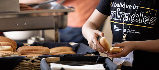 Volunteer opening a hot dog bun at the Children's Bash