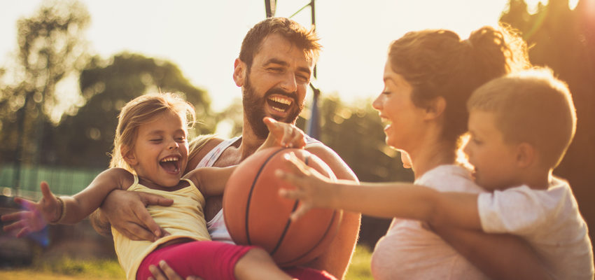 Image of family laughing and playing basketball together