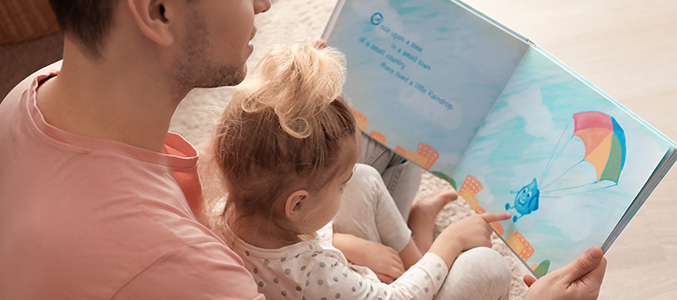 Father and his daughter reading book on floor in children room