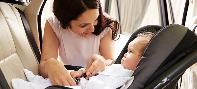 places to stay / mom strapping baby into car seat