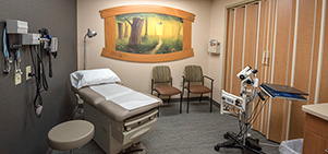 Medical exam room with an exam table, two chairs, and some equipment