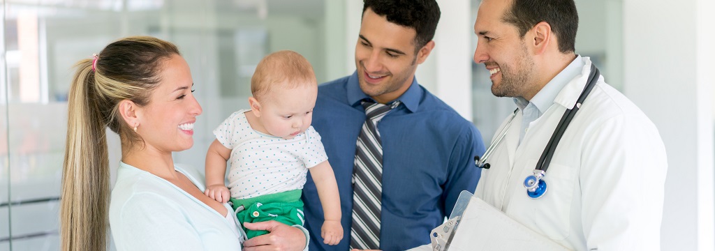 Image of doctor smiling and talking to family with a young baby